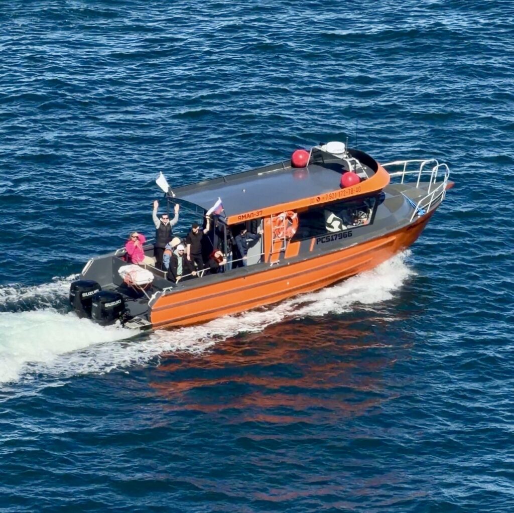 Orange tour boat cruising on the Barents Sea near Teriberka