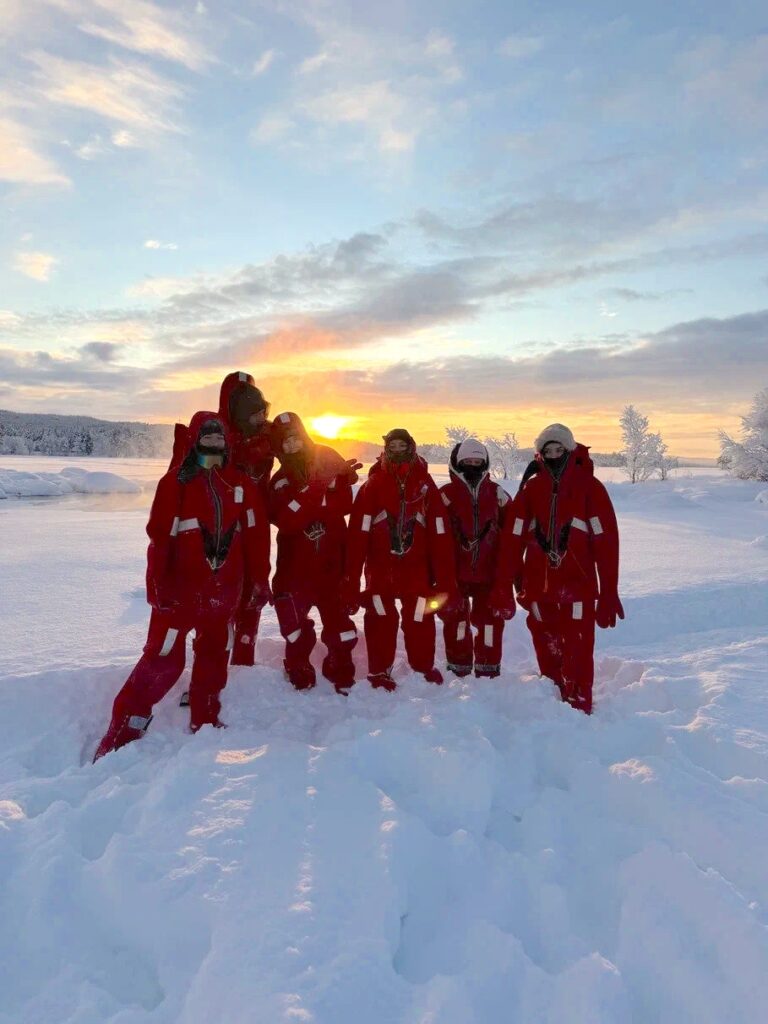Guests in protective suits on snow at sunset