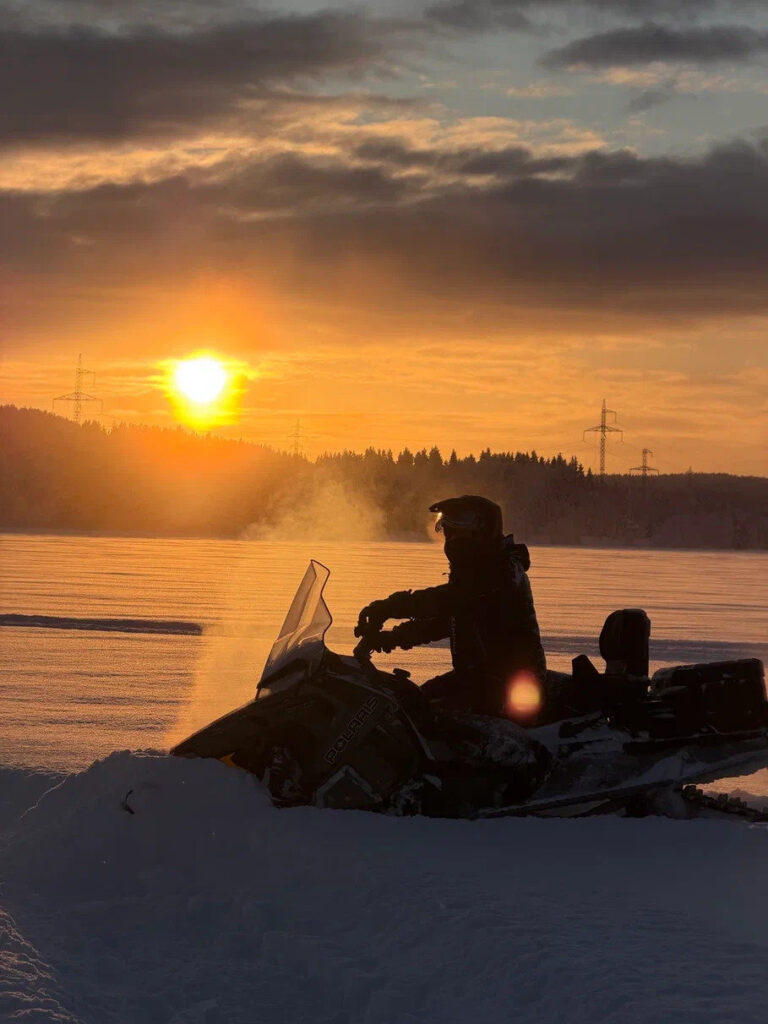 Snowmobile rider on snow at sunset