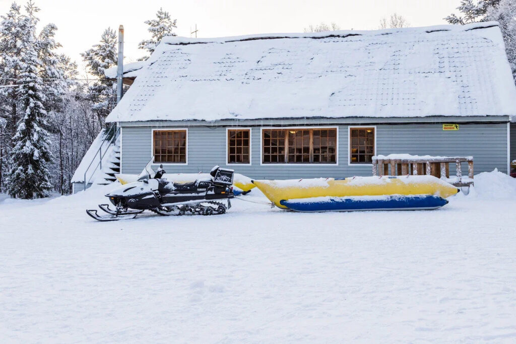 Snowmobiles beside a snow-covered forest cabin