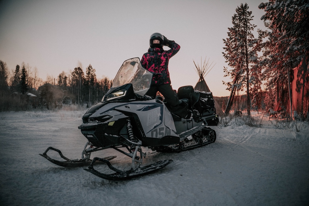 Snowmobile beside a winter forest at dusk
